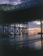 ENGLAND, East Sussex, Brighton, Sunset seen through Brighton Pier from the beach at low tide