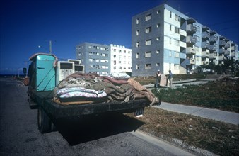 CUBA, Havana , Blocks of flats with truck parked in the foreground and two men carrying furniture