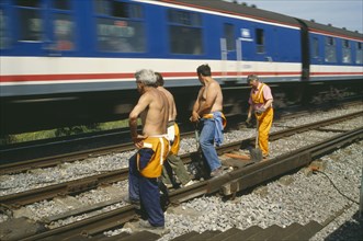 TRANSPORT, Rail, Trains , Railway workers standing on tracks as train passes.
