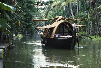 INDIA, Kerala, Backwaters, Old rice boat now used as a floating hotel on canal.
