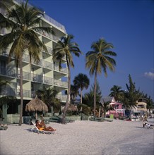 USA, Florida , Fort Myers, Hotels next to sandy beach lined with palm trees and sunbathers on the
