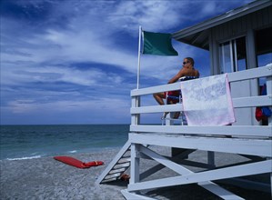 USA, Florida , Sarasota, Lido Beach. Lifeguard man sitting on high stall looking out to sea in