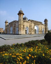 BANGLADESH, Dhaka, Lalbagh Fort.  Exterior facade with paving and orange flowers in the foreground.