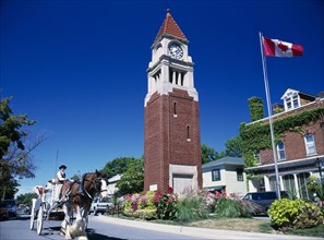 CANADA, Ontario , Niagara on the Lake, Queen Street Clock Tower with Canadian flag flying. Horse