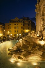 ITALY, Lazio , Rome, Trevi Fountain at night with people siting around the fountain