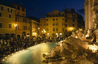 ITALY, Lazio, Rome, Trevi Fountain at night with people sitting around the fountain