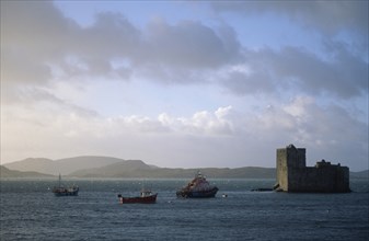 SCOTLAND, Outer Hebrides, Isle of Barra, Castle Bay.  Kisimul Castle overlooking sea and fishing