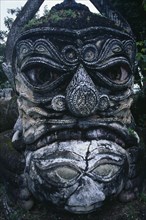 LAOS, Vientiane , Buddha Park.  Detail of fierce stone sculpture face.
