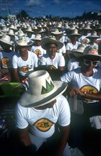 CUBA, Santiago , Crowd of seated men and women wearing matching hats and T-shirts for the July 26th