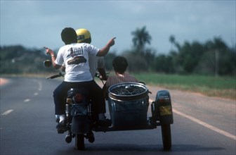 CUBA, Havana, View from behind a motorcycle and sidecar with passengers