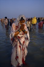 INDIA, West Bengal, Sagar Island, Woman pilgrim praying during three day Sagar bathing festival at