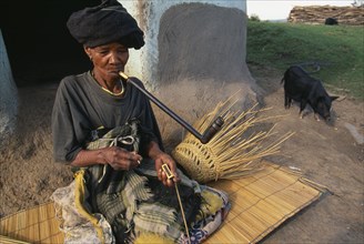 SOUTH AFRICA, Eastern Cape, Coffee Bay, Elderly Xhosa woman making basket and smoking long pipe.