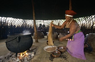 SOUTH AFRICA, Kwa Zulu Natal , Eshowe, Shakaland  Zulu woman making beer shaking sorgum from a