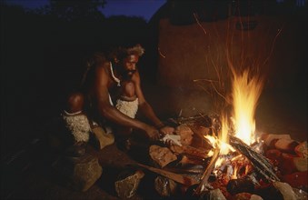 SOUTH AFRICA, Kwa Zulu Natal , Eshowe, Zulu man making a spear over an open fire at night outside
