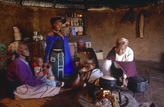 SOUTH AFRICA, Kwa Zulu Natal , Msinga, Zulu women and children cooking inside a Zulu hut or indlu.