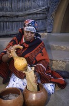 SOUTH AFRICA, Qwa Qwa, Basotho Cultural Village, Basotho woman pouring beer into a strainer from a