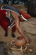 SOUTH AFRICA, Kwa Zulu Natal , Eshowe, Zulu woman preparing fire for firing pot.