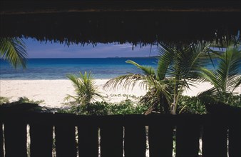PACIFIC ISLANDS, Fiji, Caqelai Island, View of beach and sea through palms framed by a thatched hut