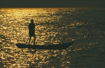 TANZANIA, Lake Tanganyika , Mokoro canoe raft paddler on lake at sunset