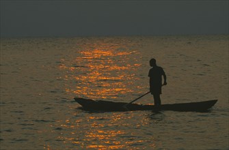 TANZANIA, Lake Tanganyika, Mokoro canoe raft paddler on water at sunset