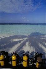 MALDIVES, Nika Island, View out to sea with scuba diving tanks on the beach in the shadow of