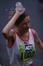 10088209 SPORT Athletics  Marathon Competitor in London Marathon pouring bottle of water over her head to keep cool.