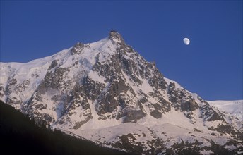 FRANCE, Rhone Alps , Chamonix, Haute Savoie. Snow covered Alps with the Moon in the sky