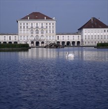 GERMANY, Bavaria,  Munich, Schloss Nymphenburg. Viewed across canal with reflection and swan on