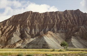 CHINA, Qinghai, View of soft eroded rocks above a wheat field in a remote valley near the Yellow