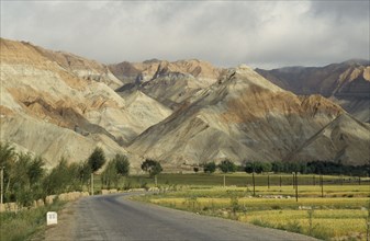 CHINA, Qinghai  , Near Yellow River , "Eroded rocks above wheat field, high altitude remote valley