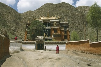 CHINA, Gansu Province, Xiahe , Labrang Tibetan Monastery with a golden roof and monks outside with