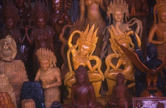CAMBODIA, Phnom Penh, Central Market.  Wood carvings of religious figures on stall.
