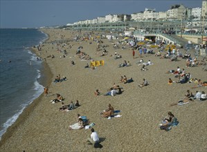 ENGLAND, East Sussex, Brighton, People sitting on the beach in summertime