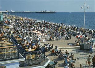 ENGLAND, East Sussex, Brighton, Seafront bars & restaurants with people sitting drinking during the