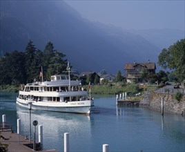 SWITZERLAND, Bern Oberland, Interlaken, White passenger ferry nearing quay with misty wooded
