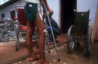 CUBA, Farabundomarti, Amputees centre. Man with pin in leg with wheel chairs all around him