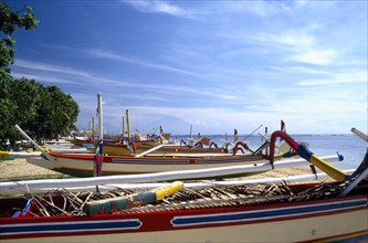 INDONESIA, Bali, Sanur Beach, View over row of colourful Outrigger fishing boats on the Beach