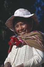 BOLIVIA, Lake Titicaca, Isla del Sol, Portrait of a smiling girl wearing a hat and shawl.