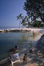 USA, Florida, Islamorada, "Cheech Lodge Beach with palms, people sitting on sun loungers in the