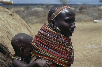 KENYA, North Frontier, Baragoi, Samburu woman wearing traditional multi-strand necklaces with child