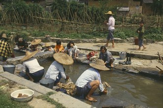 CHINA, Guangxi , Rongshui, Women and children washing clothes in village stream.