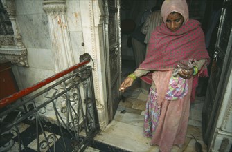 INDIA, Rajasthan , Deshnok, Karni Mata Temple interior with woman in traditional dress feeding the