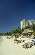 WEST INDIES, Jamaica, Ocho Rios, Sunbathers on the beach with hotel behind