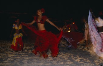 MAURITIUS, Sega Dancers, Women in red costume dancing on the beach at night. Sega is the national