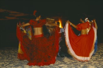 MAURITIUS, Sega Dancers, Women in red costume dancing on the beach at night.  Sega is the national