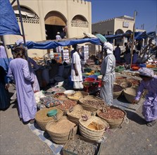 OMAN, Sharqiya, Sanaw, Souk with local people around stalls with spices displayed on ground in