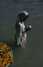 INDIA, Uttar Pradesh, Varanasi , Hindu woman praying waist deep in the water of the River Ganges.