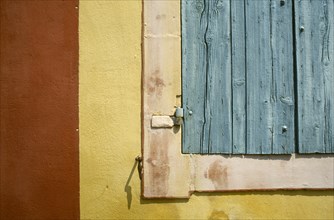 FRANCE, Rhone Alps, Rousillon, Detail of a turquoise window shutter on a yellow and red wall