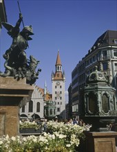 GERMANY, Bavaria, Munich, Marianplatz with people walking below the clock tower with a stone plinth