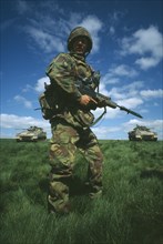 MILITARY, Soldier, Training, Soldier in camouflage standing in a field holding a gun with two